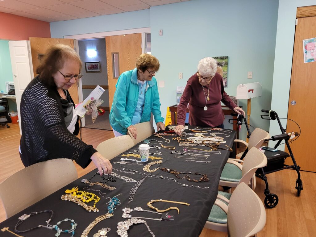 347441031_909981070074423_827361911023180138_n - Point Pleasant Three women sorting through jewelry at a community event at Point Pleasant, a trusted option for independent living near Monroeville, PA.